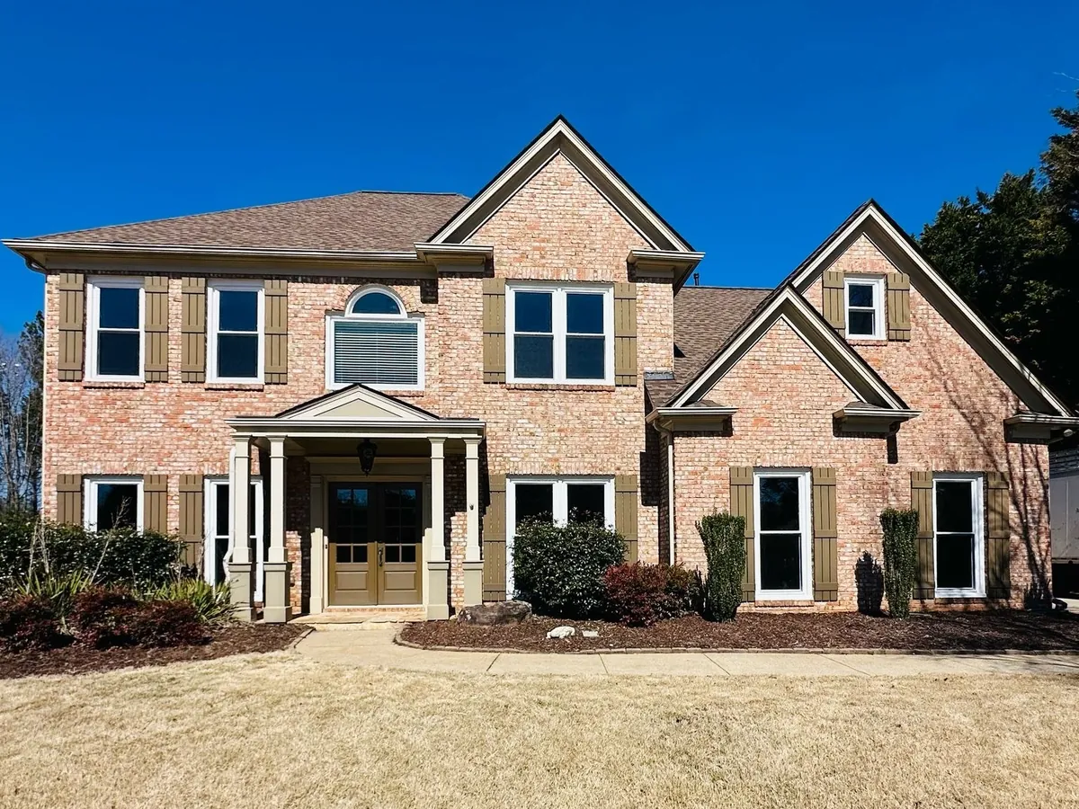 Double hung windows with grids and a half-round window on a light brick home